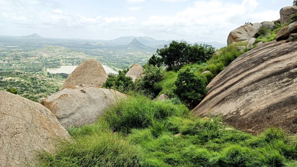 View of trekkers on the scenic trails of Minchu Kallu Day Trek, surrounded by lush greenery and mist-covered hills